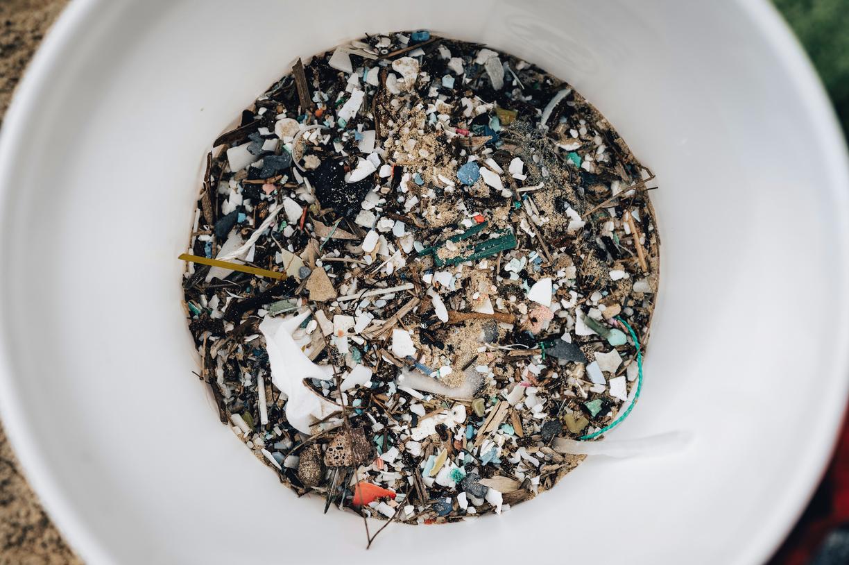 a bucket full of sand and small pieces of plastic